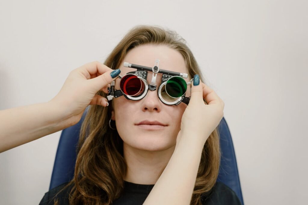 Optometrist adjusts phoropter lenses during a vision examination for a female patient.